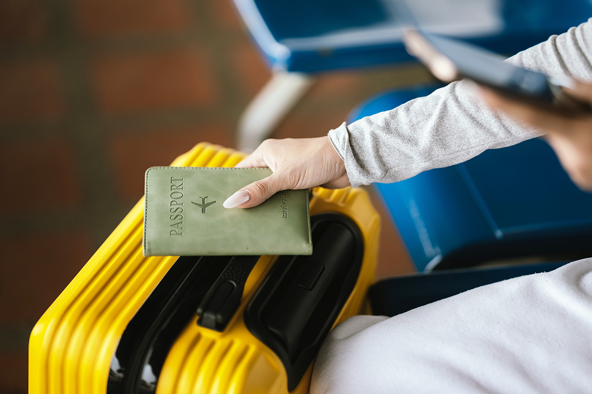 Traveler holding a passport next to a suitcase before an international flight